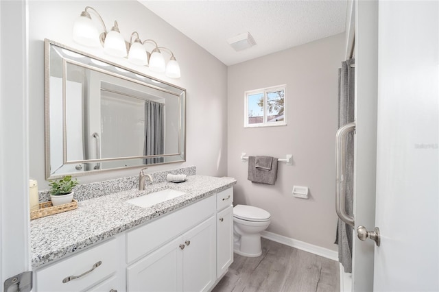 full bathroom featuring a textured ceiling, toilet, wood finished floors, vanity, and baseboards