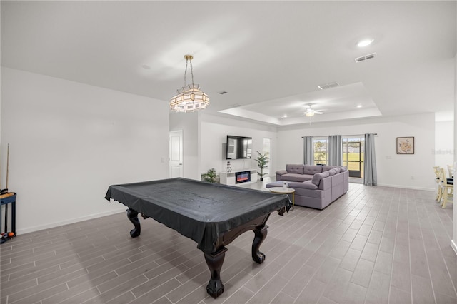 game room featuring a tray ceiling, pool table, visible vents, light wood-type flooring, and baseboards