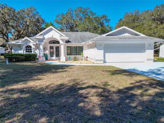 ranch-style house featuring an attached garage, driveway, french doors, stucco siding, and a front yard