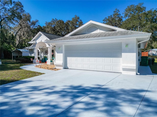 view of front facade featuring a garage, driveway, a shingled roof, and stucco siding