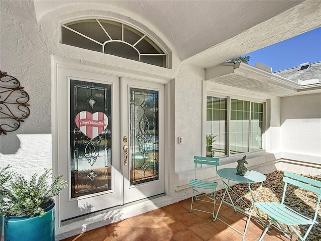 view of exterior entry featuring french doors and stucco siding