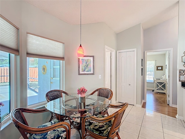 dining room with lofted ceiling, light tile patterned flooring, baseboards, and plenty of natural light