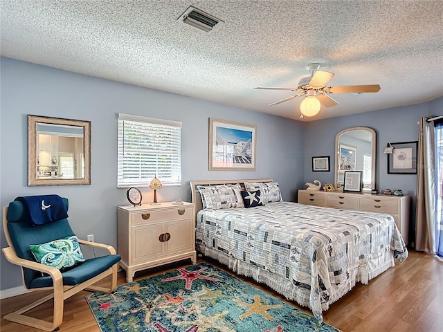 bedroom featuring baseboards, visible vents, ceiling fan, a textured ceiling, and light wood-type flooring