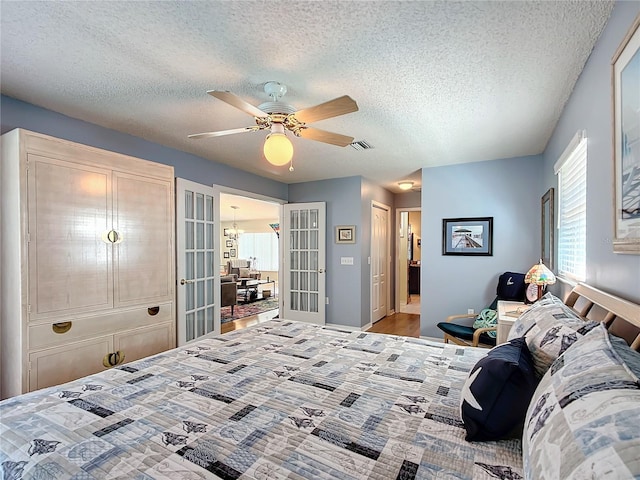 bedroom featuring a textured ceiling, visible vents, a ceiling fan, and french doors