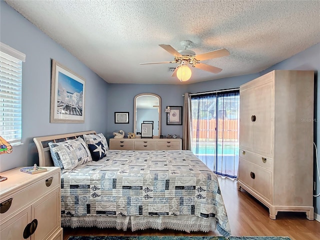 bedroom with access to exterior, light wood-type flooring, ceiling fan, and a textured ceiling