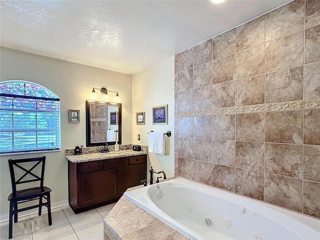 bathroom with baseboards, a tub with jets, tile patterned floors, a textured ceiling, and vanity