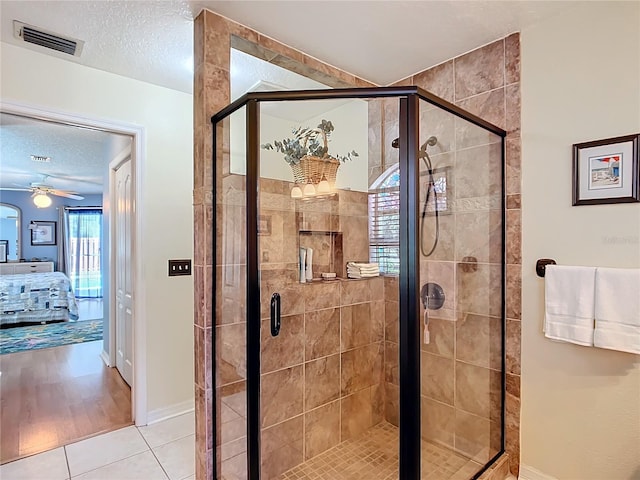 bathroom with a textured ceiling, tile patterned flooring, visible vents, a shower stall, and ensuite bath