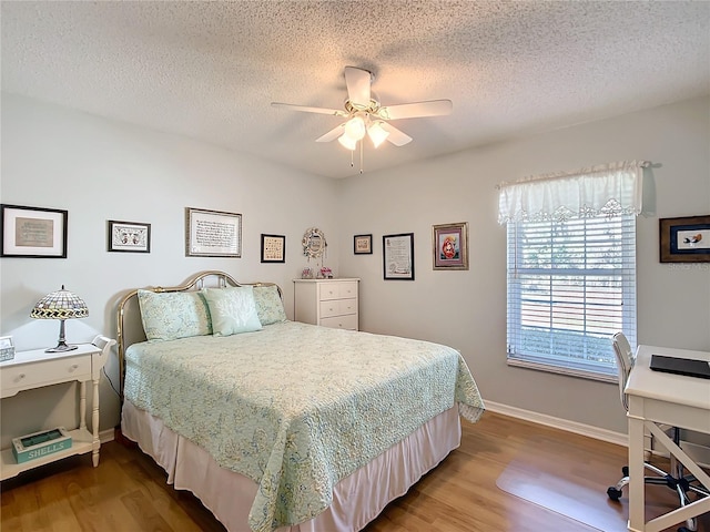 bedroom featuring a textured ceiling, baseboards, and wood finished floors