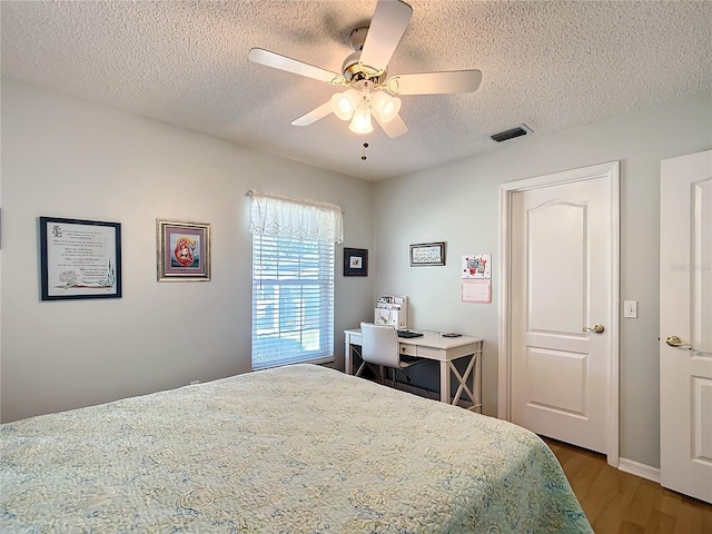 bedroom featuring visible vents, ceiling fan, a textured ceiling, and wood finished floors