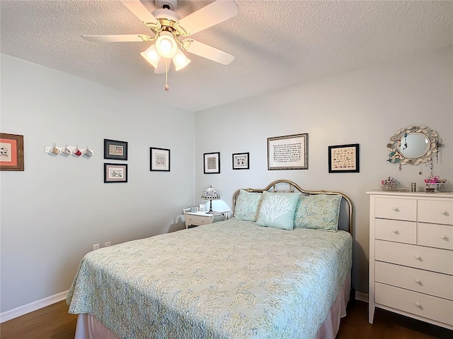 bedroom featuring a ceiling fan, a textured ceiling, baseboards, and dark wood-type flooring