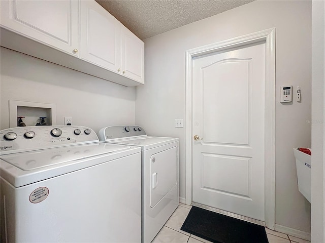 laundry area with cabinet space, a textured ceiling, washing machine and clothes dryer, and light tile patterned floors