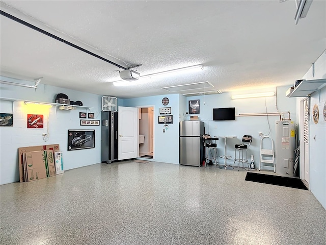 garage featuring water heater, concrete block wall, freestanding refrigerator, and a garage door opener