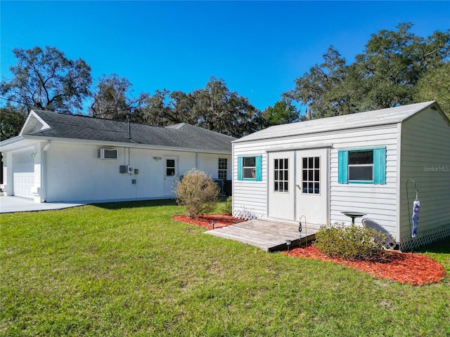 back of house with a garage, an outdoor structure, and a lawn