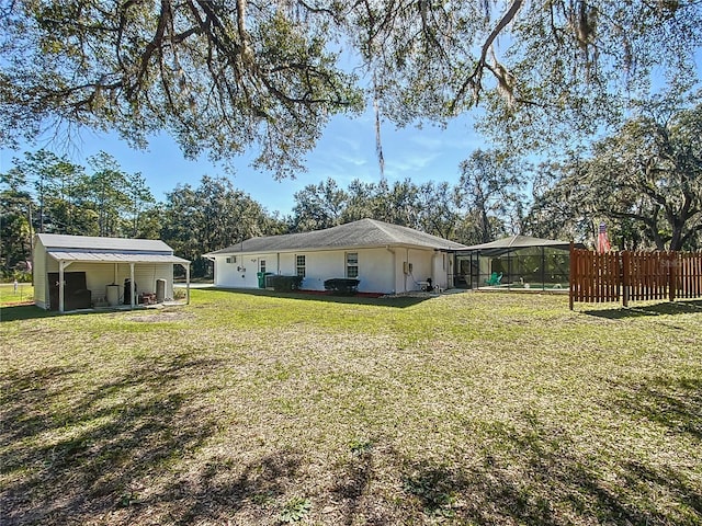 rear view of property with a lanai and a lawn