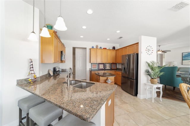 kitchen featuring visible vents, appliances with stainless steel finishes, a peninsula, pendant lighting, and a sink