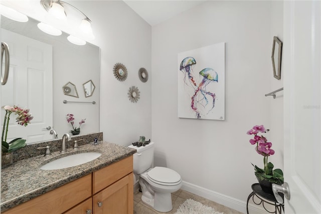 bathroom with toilet, tile patterned flooring, vanity, and baseboards