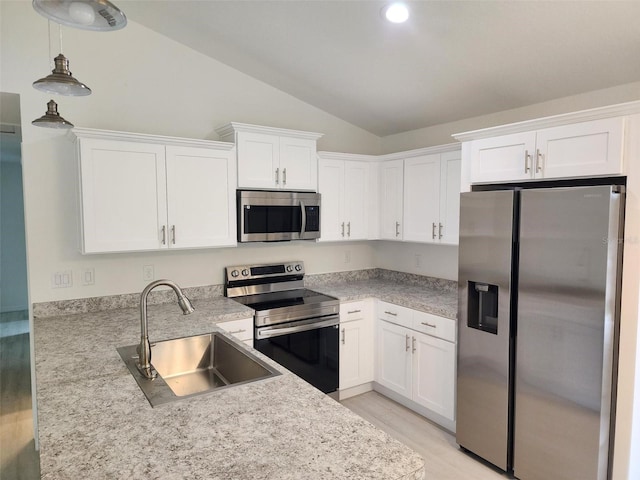 kitchen with white cabinets, lofted ceiling, appliances with stainless steel finishes, light countertops, and a sink