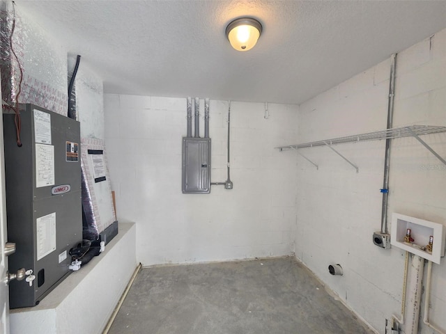 interior space featuring hookup for a washing machine, concrete block wall, electric panel, and a textured ceiling