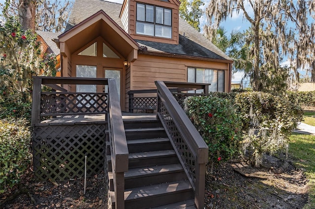 exterior space featuring a shingled roof and stairs