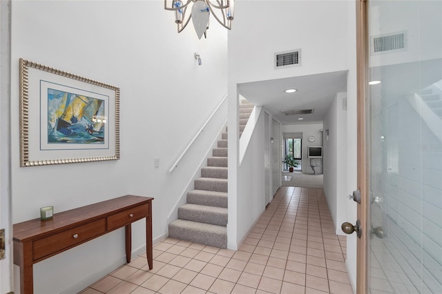 foyer featuring stairway, a high ceiling, visible vents, and light tile patterned flooring