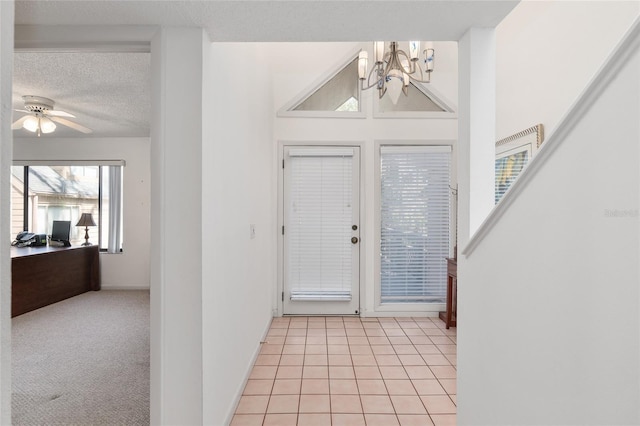 foyer entrance featuring light carpet, baseboards, light tile patterned flooring, a textured ceiling, and ceiling fan with notable chandelier