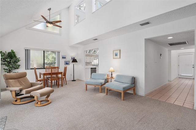 living area featuring light tile patterned floors, a ceiling fan, visible vents, and light colored carpet