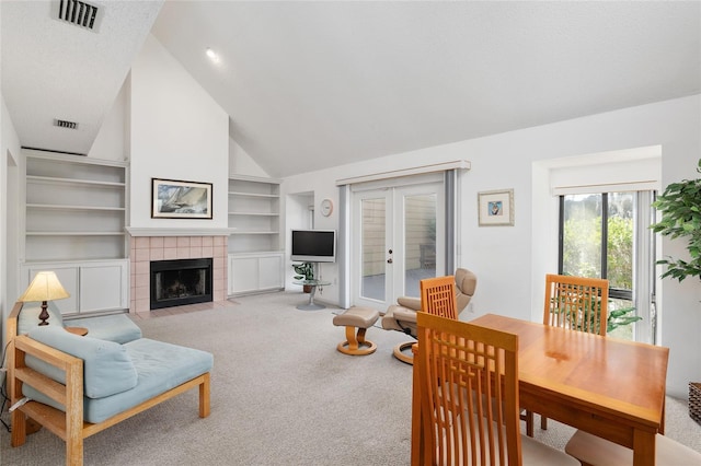 living room featuring built in features, french doors, a fireplace, visible vents, and light carpet