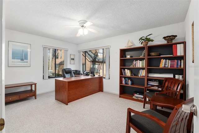 office space featuring a textured ceiling, a ceiling fan, and light colored carpet