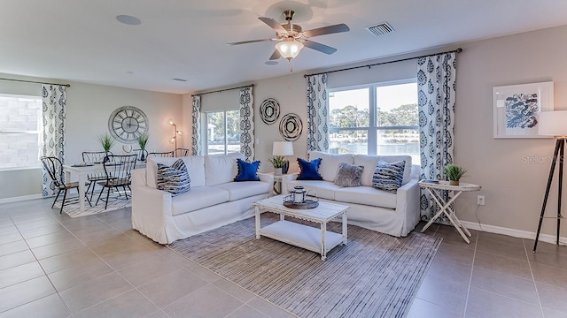 tiled living area with baseboards, visible vents, and ceiling fan