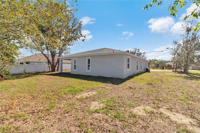 exterior space with stucco siding, fence, and a lawn