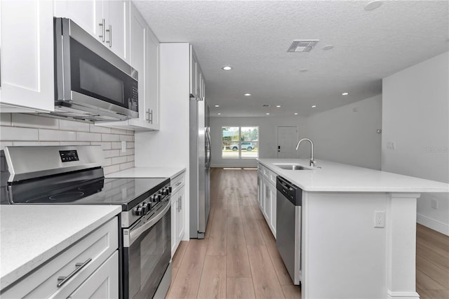 kitchen featuring stainless steel appliances, white cabinets, light countertops, and a sink