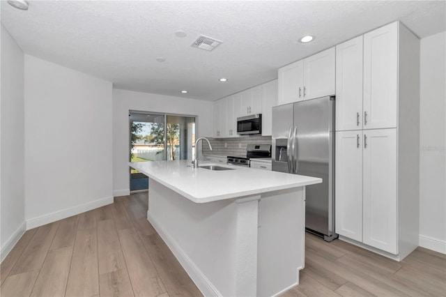kitchen featuring stainless steel appliances, visible vents, an island with sink, and white cabinetry