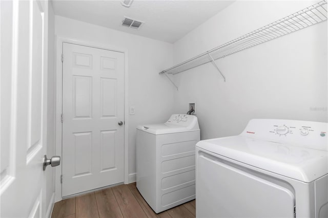 laundry room featuring laundry area, washing machine and clothes dryer, visible vents, and light wood-style floors