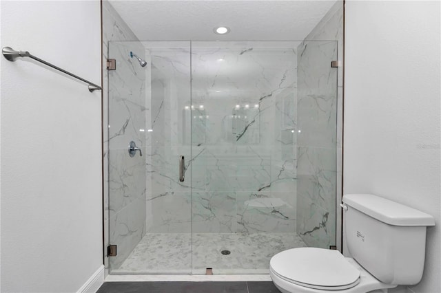 bathroom featuring toilet and a marble finish shower