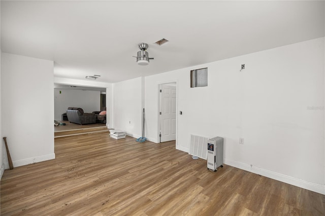 spare room featuring visible vents, baseboards, and wood finished floors