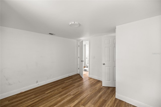 empty room with visible vents, baseboards, and dark wood finished floors