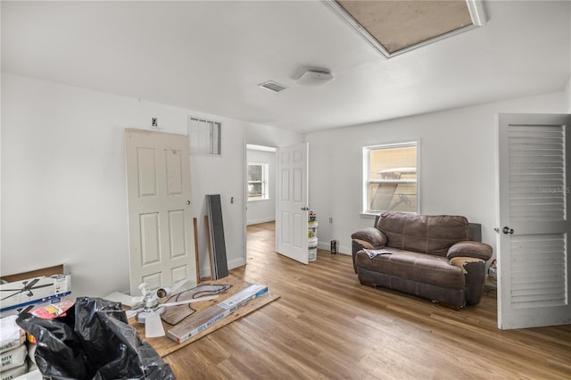 living room featuring light wood-style floors, attic access, visible vents, and baseboards