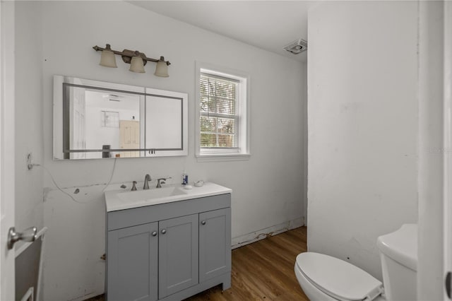 half bath with vanity, toilet, and wood finished floors