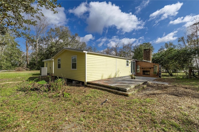 rear view of property with a chimney, central AC, and a yard