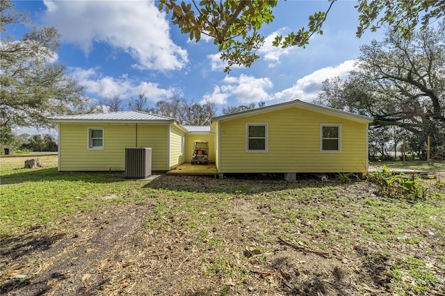 back of property with metal roof, a lawn, and central air condition unit