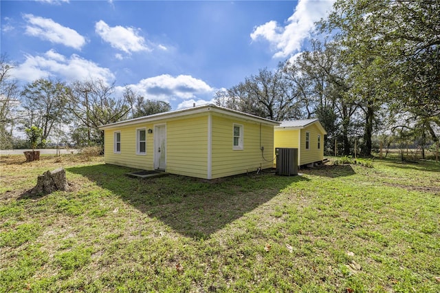 rear view of property with metal roof, central AC, and a lawn