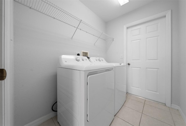 laundry room featuring laundry area, baseboards, light tile patterned flooring, and washing machine and clothes dryer