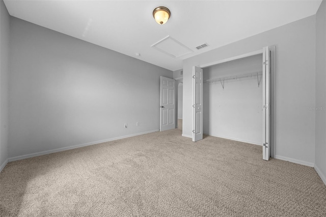 unfurnished bedroom featuring carpet floors, visible vents, baseboards, a closet, and attic access