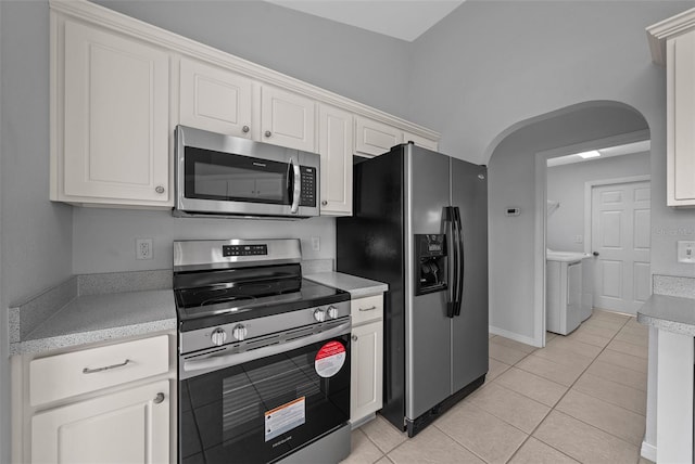 kitchen featuring appliances with stainless steel finishes, washing machine and dryer, light countertops, and arched walkways