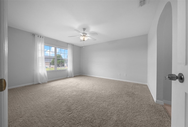 unfurnished room featuring ceiling fan, arched walkways, visible vents, baseboards, and carpet