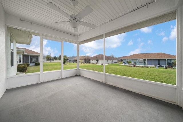 unfurnished sunroom featuring a residential view and a ceiling fan