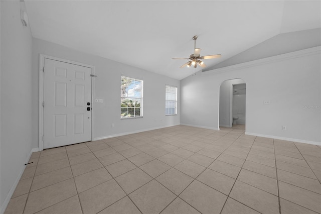 interior space with arched walkways, ceiling fan, lofted ceiling, and baseboards