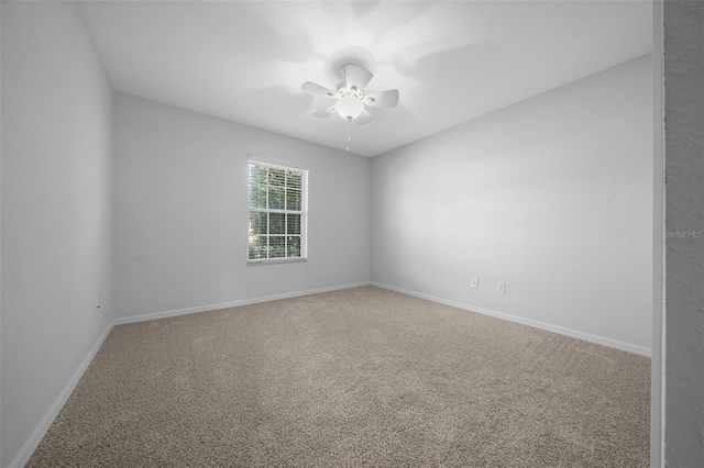 carpeted spare room featuring ceiling fan and baseboards