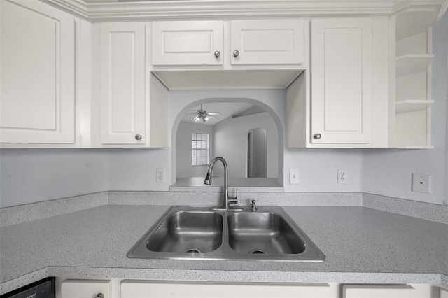 kitchen featuring arched walkways, open shelves, light countertops, white cabinets, and a sink