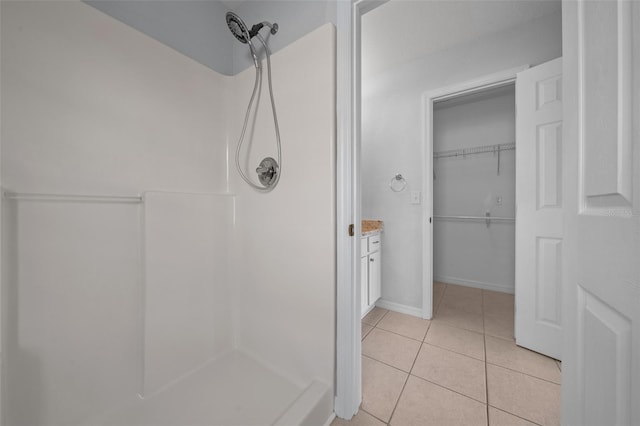 full bath featuring tile patterned flooring, baseboards, and walk in shower